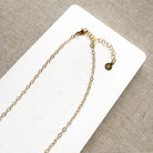 Clasp detail of multicolored gemstone necklace on a white background
