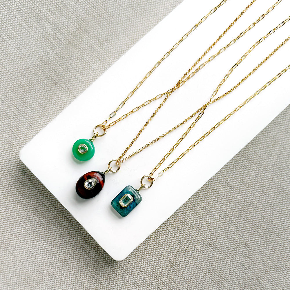 Gold chains with gemstone charms on a white tray