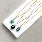 Gold chains with gemstone charms on a white tray