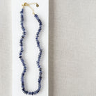Iolite gemstone necklace on a white dish with a beige fabric background