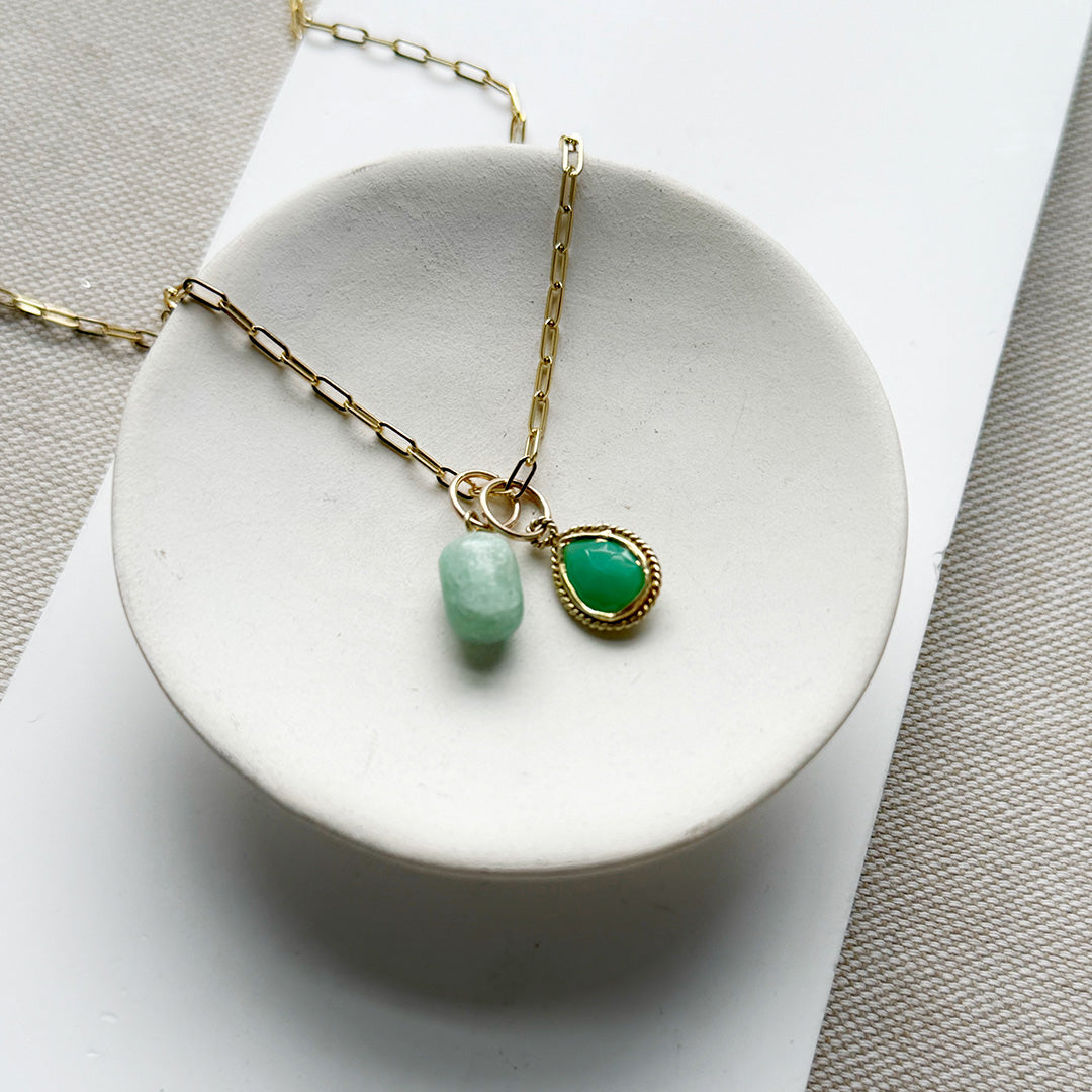 Gold necklace with green gemstones on a white dish