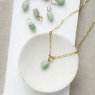 Jade charm in a cylinder cut on a gold chain in a white dish