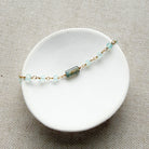 Bracelet with aqua chalcedony gemstones on a white dish against a beige background