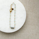 Gold bracelet with aqua chalcedony gemstones on a white marble surface