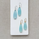 Pair of blue chalcedony teardrop earrings on a white card with a gray background