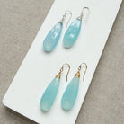 Pair of blue chalcedony teardrop earrings on a white card with a textured background