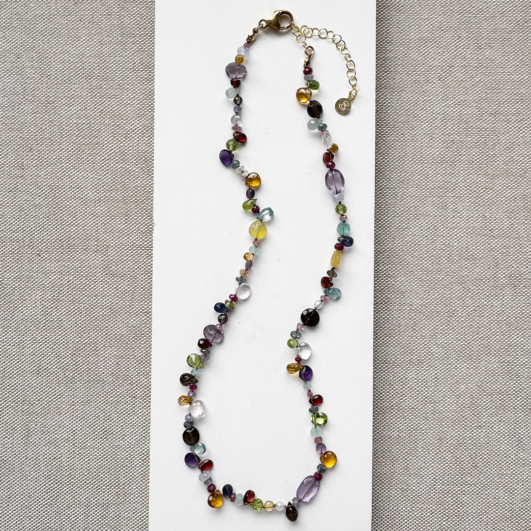 Multicolored gemstone necklace on a white card with a gray background