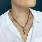 A close-up of a person wearing a Sapphire Knotted Necklace with Hessonite Garnet pendant