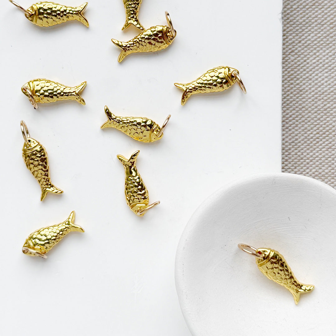 Small gold fish charms on white background