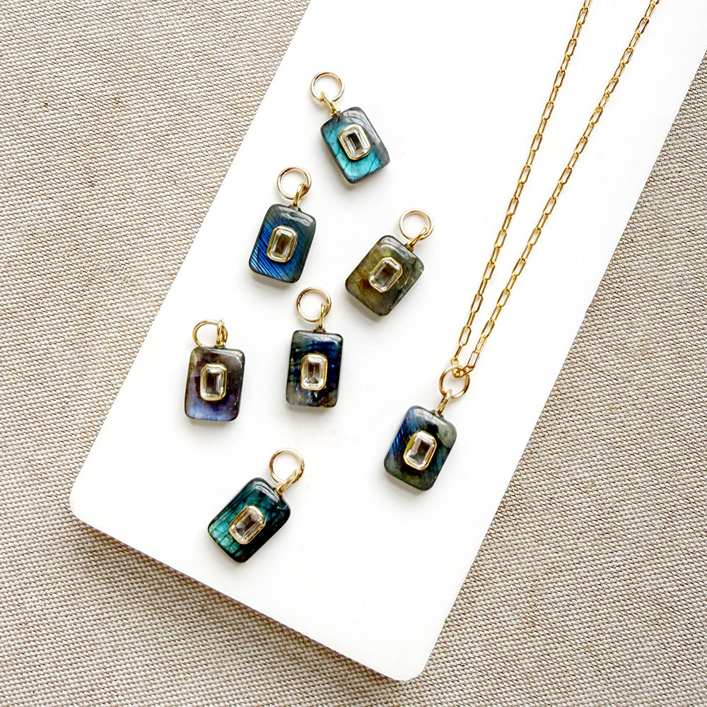Rectangular labradorite charm with inset cz stone on a white dish