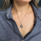 Woman wearing ectangular labradorite charm with inset cz stone on a gold chain