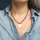Close up of woman wearing gemstone necklace with carved pendant