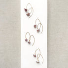 Irregular lavender pearl on a gold v-wire earring, displayed on a white card