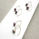 Irregular lavender pearl on a gold v-wire earring, displayed on a white card