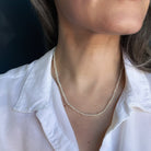 Person wearing a lemon quartz beaded gem necklaces with a white shirt against a dark background