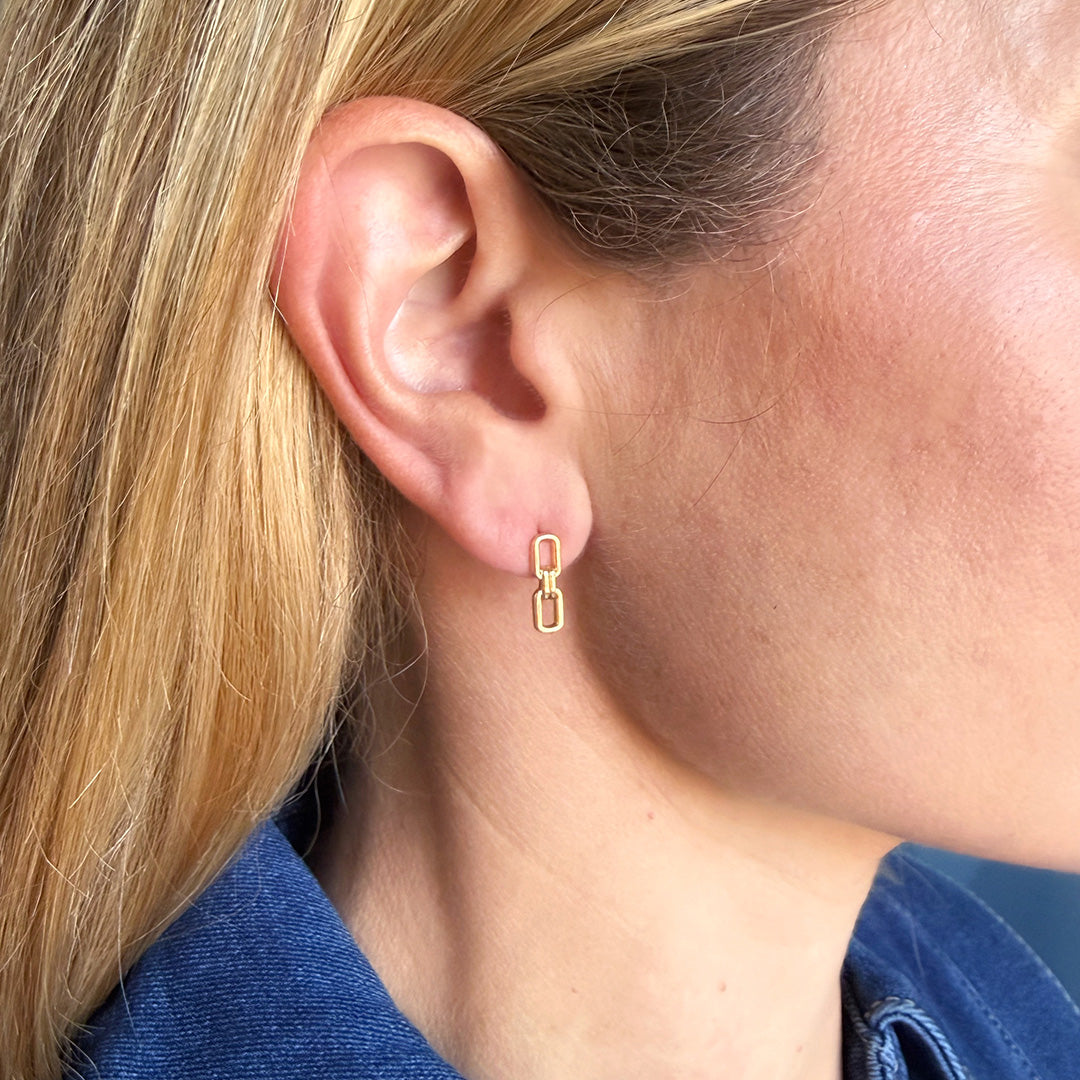 Close up of woman wearing a chain link stud in gold