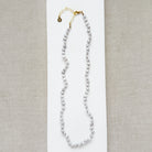 Pearl necklace with gold clasp on a light gray background