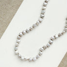 Pearl necklace with gold clasp on a light gray background