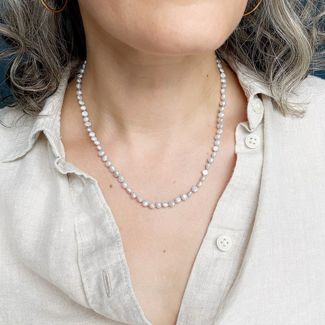 Person wearing a pearl necklace with a light-colored shirt