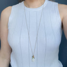 Woman wearing a light blue tank top and long gemstone cluster on a gold chain
