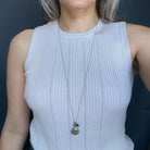 Woman wearing a light blue tank top and long gemstone cluster on a gold chain