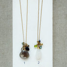 Two long gemstone cluster necklaces in gold on a white background