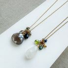 Two long gemstone cluster necklaces in gold on a white background