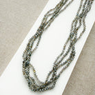 Small labradorite gems knotted necklace on a white surface with a beige background