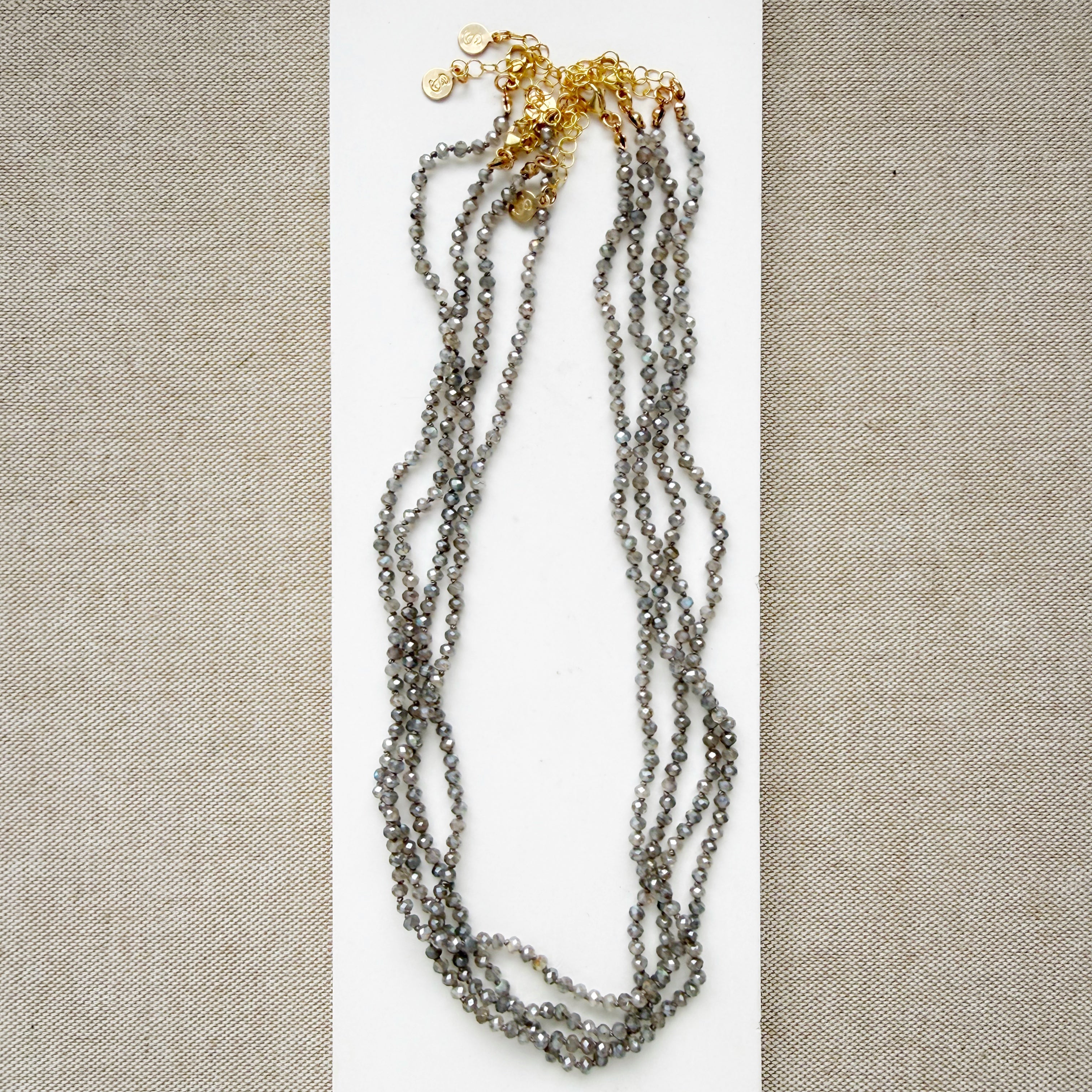 Small labradorite gems knotted necklaces on a white surface with a beige background
