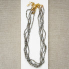 Small labradorite gems knotted necklaces on a white surface with a beige background