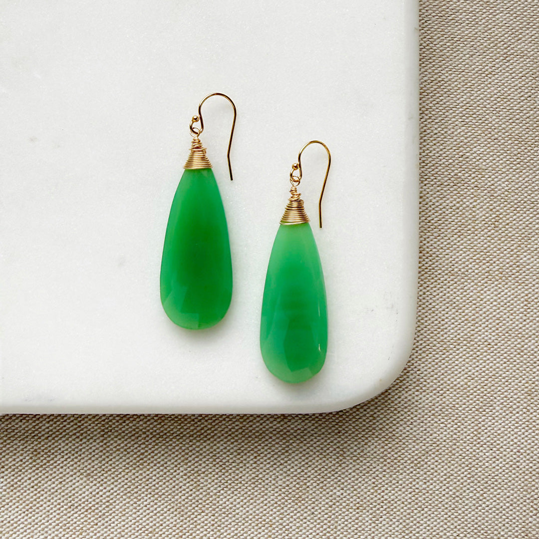Green chalcedony teardrop earrings with gold wire hooks on a white surface.