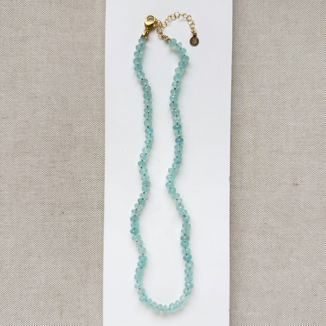 Aqua chalcedony necklace on a white card against a beige background