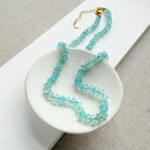 Aqua chalcedony beaded necklace on a white dish with a neutral background
