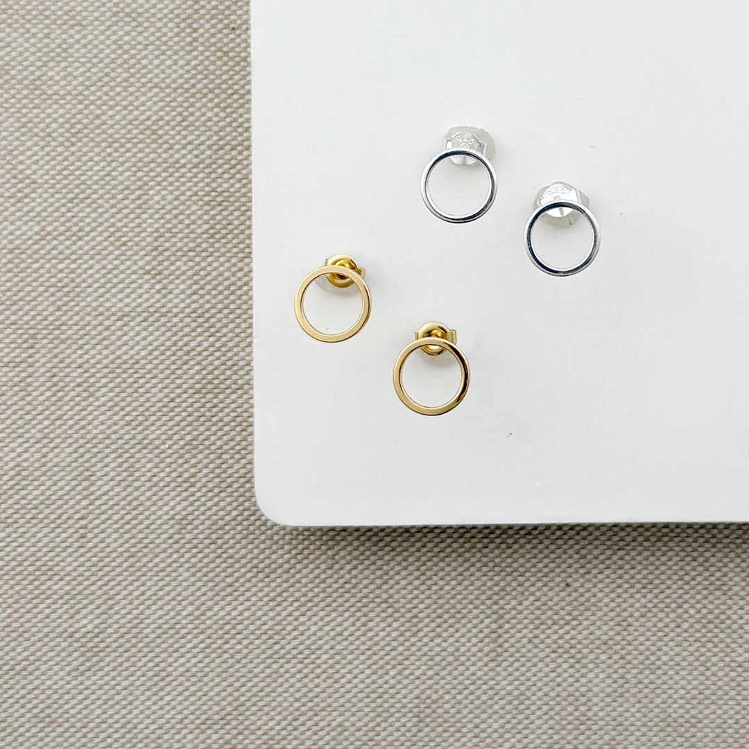 Open circle studs in gold and silver on a white background