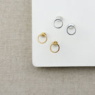 Open circle studs in gold and silver on a white background
