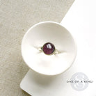 Round smooth cut mauve spinel ring in a white dish
