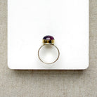 Side view of round smooth cut mauve spinel ring on a white dish