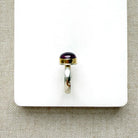 side view of round smooth cut mauve spinel ring on a white dish