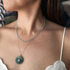 Close up of woman wearing a labradorite pendant with small inset blue quartz stone on a gold chain