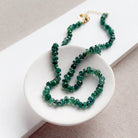 Green kyanite gemstone necklace on a white dish with a neutral background