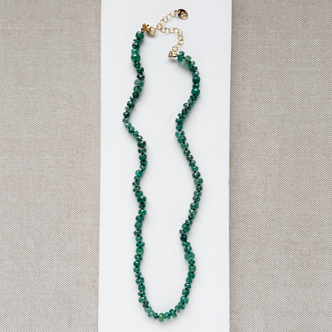 Green kyanite gemstone necklace on a white plate with a neutral background