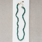 Green kyanite gemstone necklace on a white plate with a neutral background