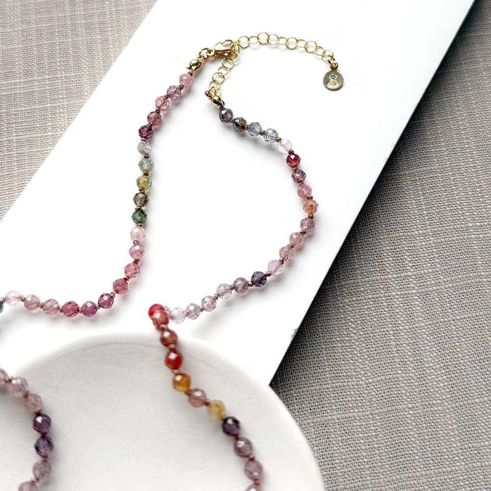 Clasp detail of spinel knotted necklace on a white plate
