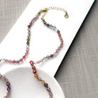 Clasp detail of spinel knotted necklace on a white plate