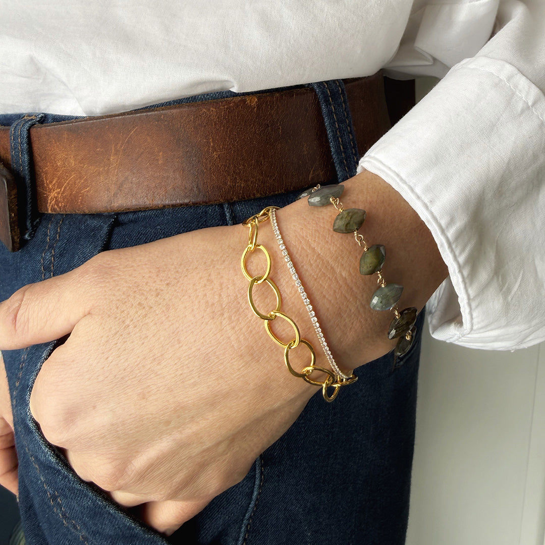 Close up of woman's wrist wearing micro style CZ tennis bracelet stacked with other bracelets