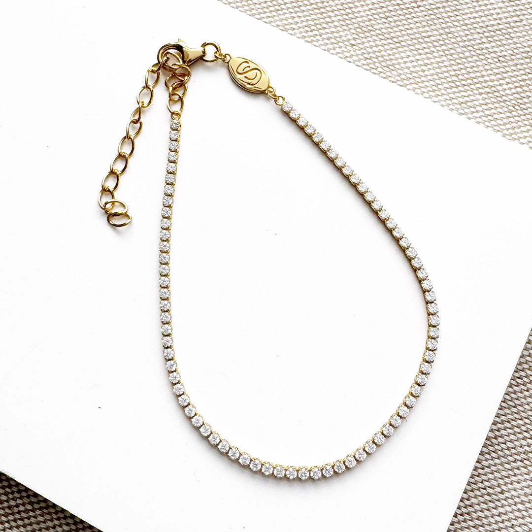 Gold and CZ micro style tennis bracelet on a white surface