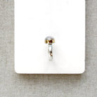 Side view of round moonstone mixed metal ring on a white background
