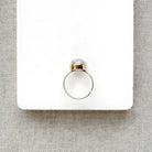 Side view of round moonstone mixed metal ring on a white background