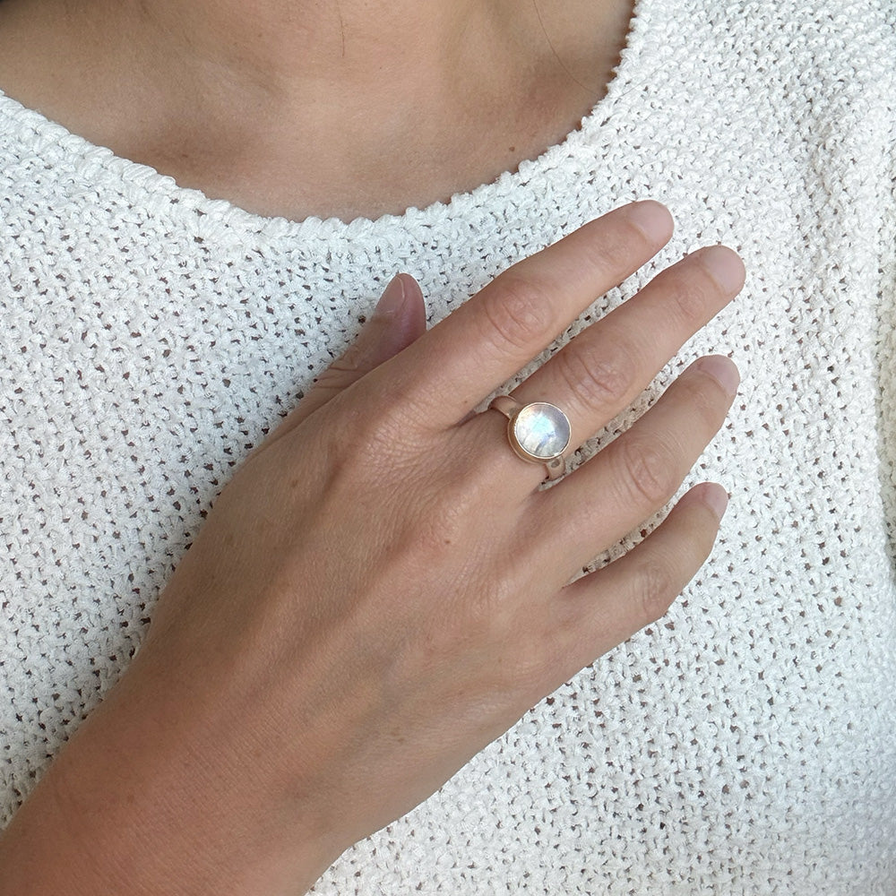 Round moonstone mixed metal ring on a womans hand