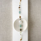 Multicolored chunky gemstone bracelet on a white square card with a textured beige background